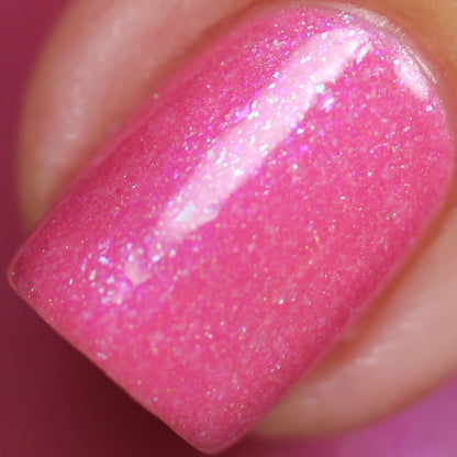 A close-up of a fingernail painted with PI Colors' Strawberry Sundae.002 Pink Nail Polish unveils a glossy pink finish accentuated by shimmering holographic powder. The polish catches the light, creating a dazzling effect, while the surrounding skin looks smooth and expertly manicured.