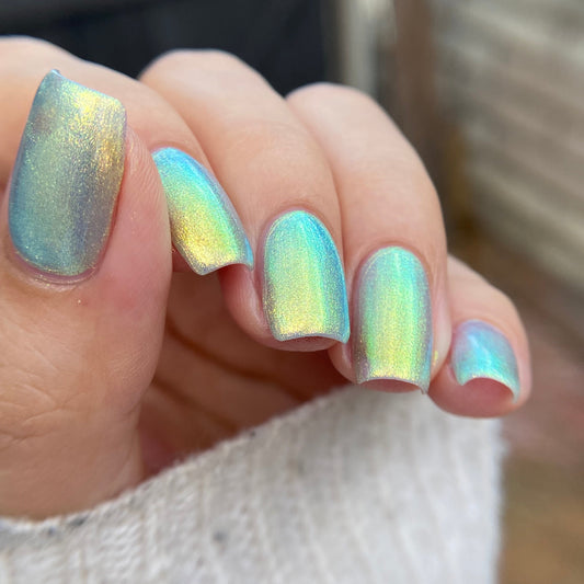 Close-up of a hand with iridescent nail polish on a blurred background