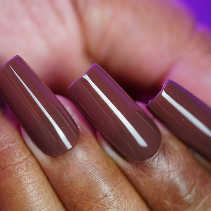 A close-up of three coffin-shaped acrylic nails painted with PI Colors' Chocolate Turtle.411, a glossy chocolate brown creme, with one nail showing a noticeable break near the tip.
