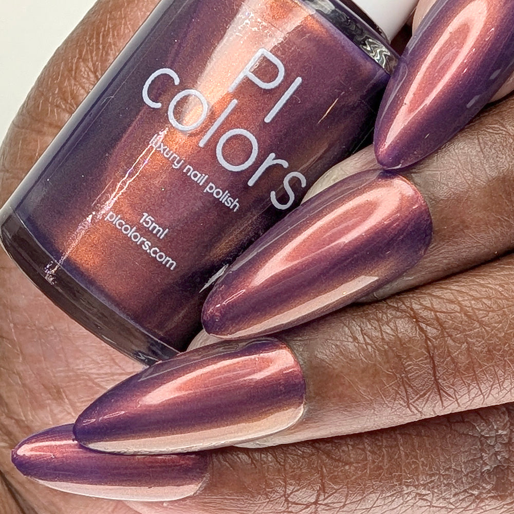 Hand with purple nail polish holding a bottle of PI Colors nail polish.
