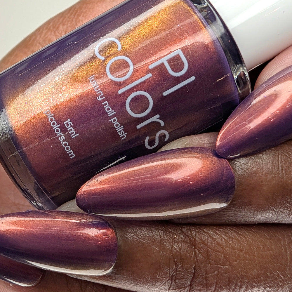 Hand with purple nail polish holding a bottle of PI Colors nail polish.