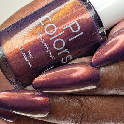 Hand with purple nail polish holding a bottle of PI Colors nail polish.