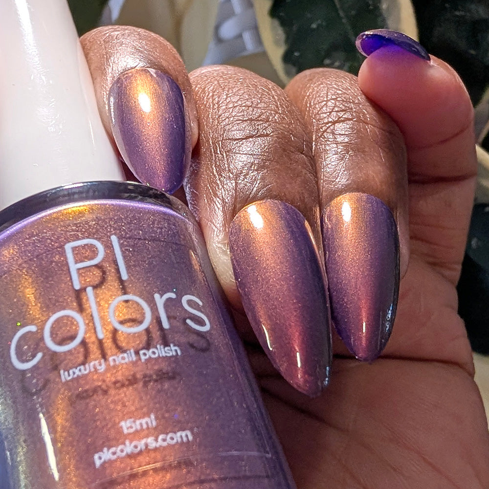 Hand with purple nail polish holding a bottle of PI Colors nail polish.