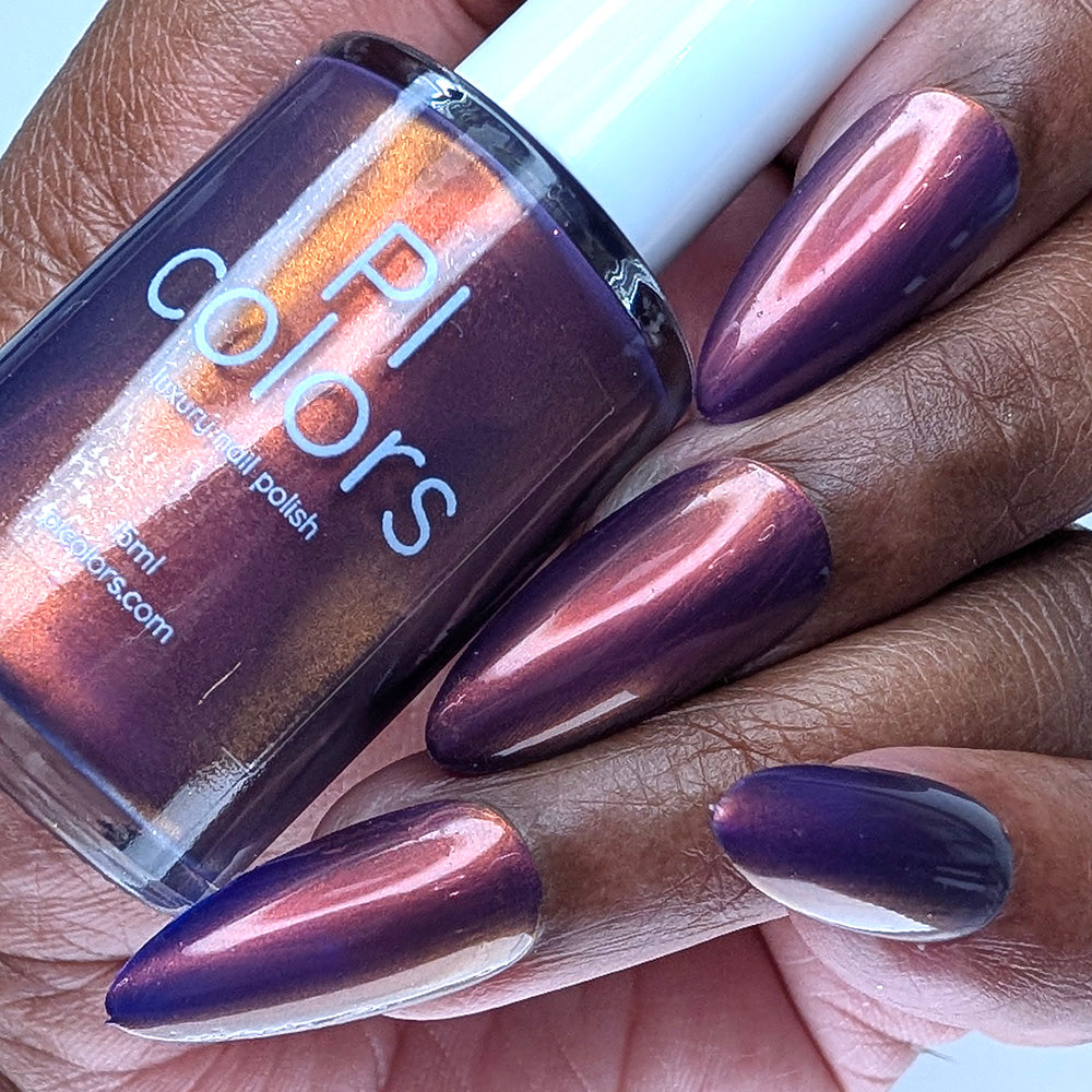 Hand with purple nail polish holding a bottle of PI Colors nail polish.