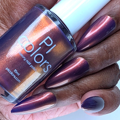Hand with purple nail polish holding a bottle of PI Colors nail polish.