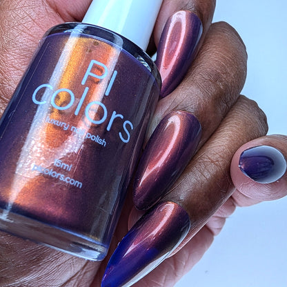 Hand with purple nail polish holding a bottle of PI Colors nail polish.