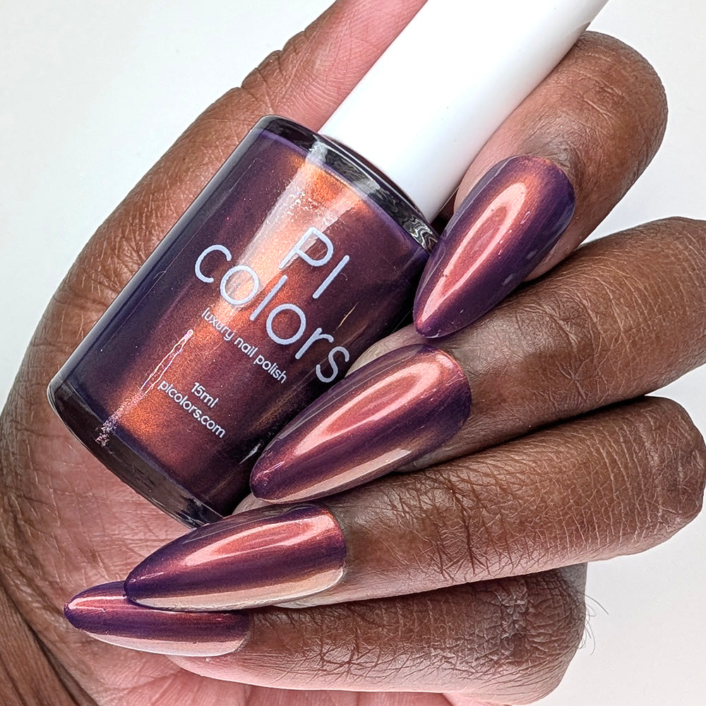 Hand with purple nail polish holding a bottle of PI Colors nail polish.