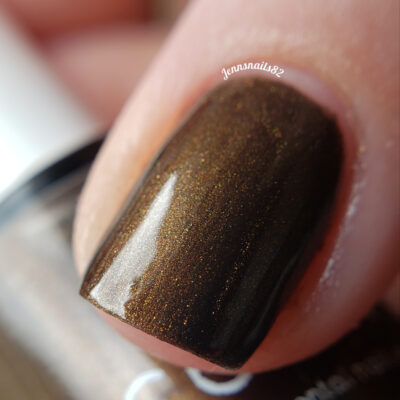 Close-up of a fingernail painted with Eclair.001 Brown Nail Polish by PI Colors, featuring a dark chocolate brown shade. The surface reflects light, highlighting the handmade polish's metallic sheen.