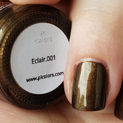 A finger with shiny, dark chocolate brown nail polish, reflecting the allure of luxury nail lacquer, rests next to a nail polish bottle cap labeled "Eclair.001" from PI Colors at plcolors.com.