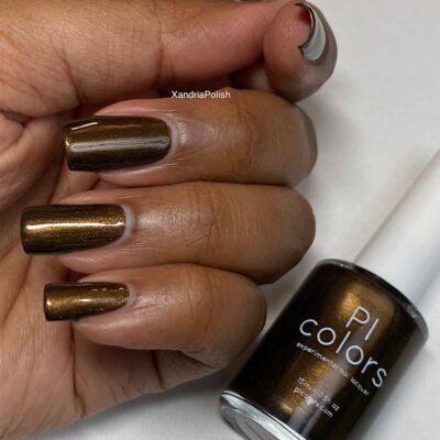 A close-up of a hand with long nails adorned in the luxurious shade of PI Colors' Eclair.001 Brown Nail Polish. The bottle is visible, displaying the same sophisticated dark chocolate hue.