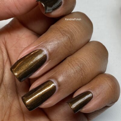 A hand with neatly manicured fingers is shown, featuring nails painted in PI Colors' Eclair.001 Brown Nail Polish, a glossy, dark chocolate brown lacquer with a subtle shimmer. The plain white background accentuates the rich hue of this exquisite polish.
