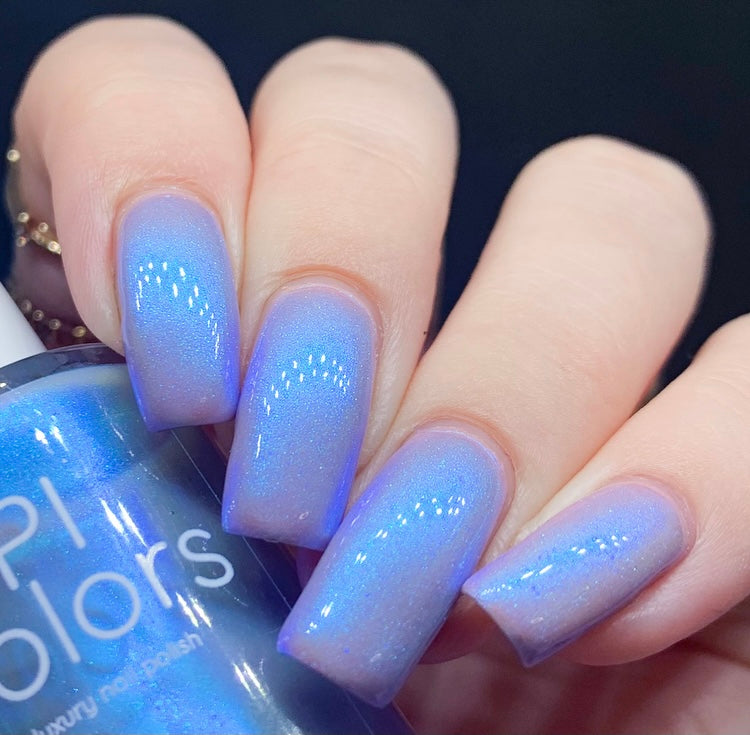 A hand displays perfectly manicured nails painted in Cloud Rainbow.303 Blue Nail Polish, showcasing an iridescent electric silver blue hue. The subtle color-shifting shimmer elegantly reflects light, while the PI Colors bottle is visible in the image.