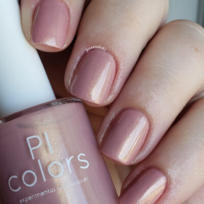 A close-up of neatly manicured fingers wearing mauve Milk Berry.073 Pink Nail Polish from PI Colors, holding the matching bottle that offers a subtle shimmer.