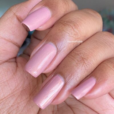 A hand showcases neatly manicured nails painted in the soft pink shade of PI Colors' Milk Berry.073 Pink Nail Polish, featuring medium-length nails with a glossy finish.