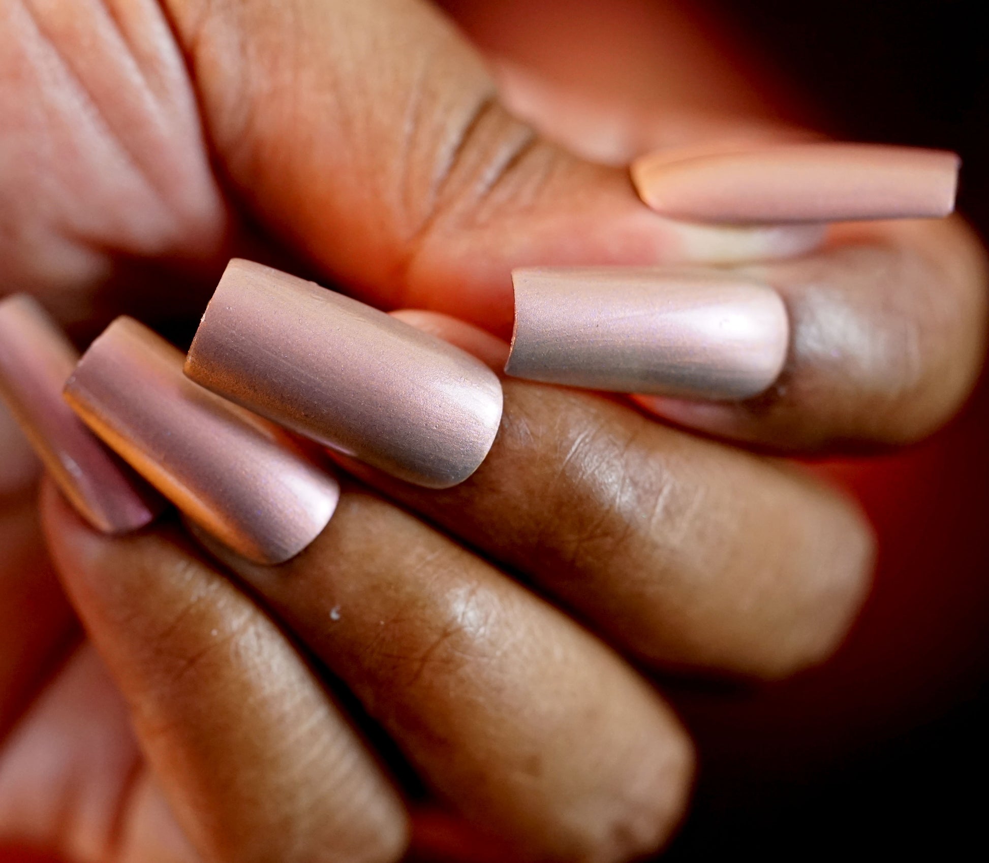 A close-up of a hand showcasing long, almond-shaped nails painted in PI Colors' Mulberry Love.205, a metallic iridescent pink. The softly blurred background highlights the glossy and smooth finish of this luxury manicure.