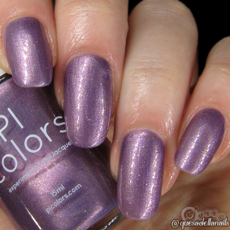 A close-up of a hand with nails painted in Star Road.001 by PI Colors, a shimmery chrome purple hue. The luxurious nail lacquer bottle, labeled with the same shade, is held between the fingers, showcasing nails adorned with a glossy, metallic finish.