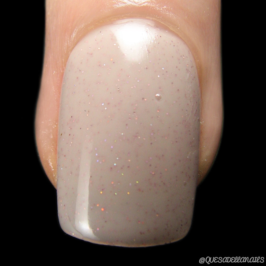 A close-up of a fingernail adorned with PI Colors' "Strawberry Milk.021," a glossy, beige nail polish featuring subtle holographic glitter. This luxury lacquer delivers a smooth, shiny finish with multicolored sparkles that beautifully catch the light.