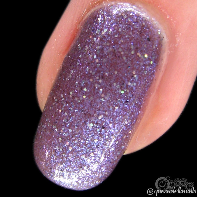 Close-up of a fingernail adorned with Unicorn Sauce.001, a sparkling purple handmade nail polish by PI Colors. The black-blue glitter finish reflects light in various colors, enhancing depth and brilliance.