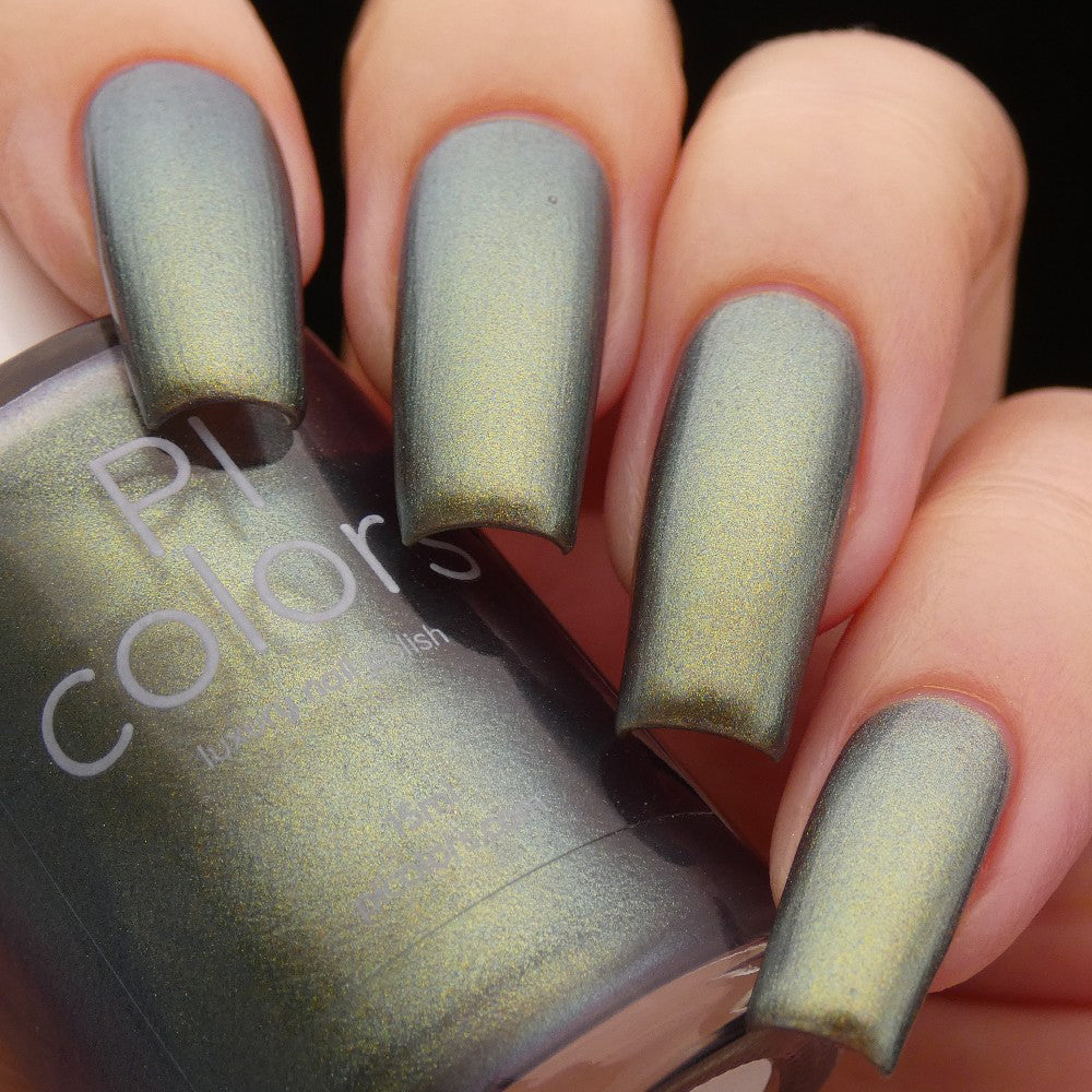 A close-up captures a hand flaunting long nails adorned with a shimmering, metallic luxury nail lacquer in the shade Light/Forest.000 Green from PI Colors. The partially visible bottle, labeled with the brand name, rests against the fingers, suggesting its multi-chrome brilliance.