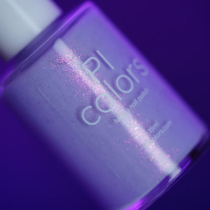 A close-up of a bottle of PI Colors nail polish named "Snowball.485," a handmade light purple shade with pink shimmer, set against a purple background.