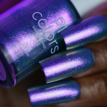 A close-up of a hand with long nails painted in shiny, metallic purple PI Colors Sugar Sparkles.451 nail lacquer. A matching bottle labeled "PI Colors" is held near the nails.